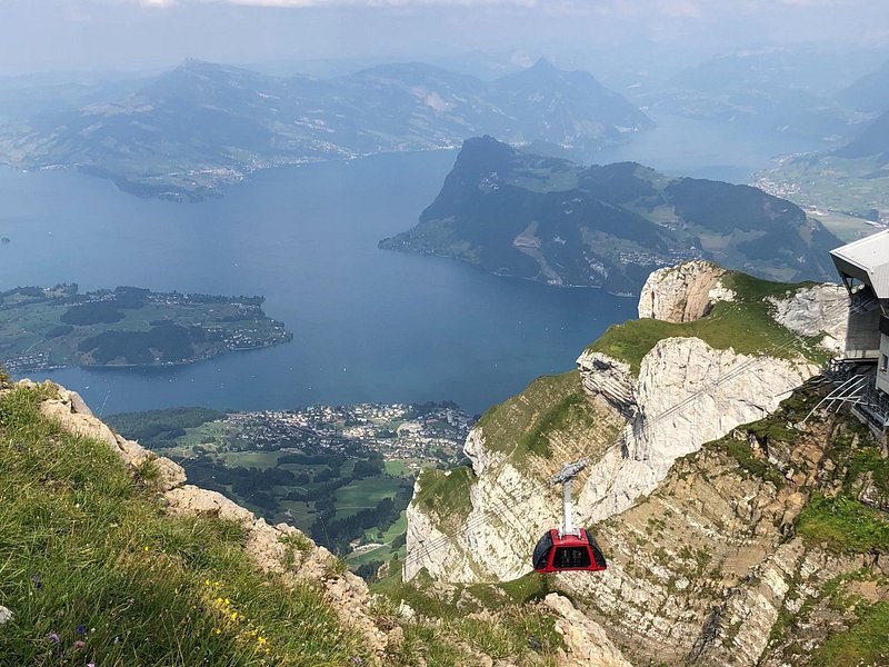 A lake far below a limestone ridge, a cable car on the slope