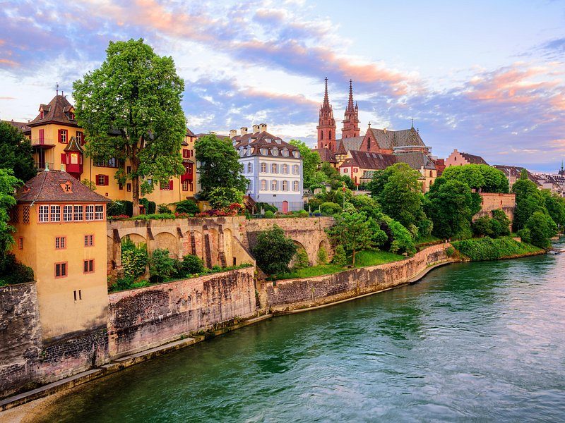 The Minster's twin red spires above the Rhine, gardens and old houses on the bank below