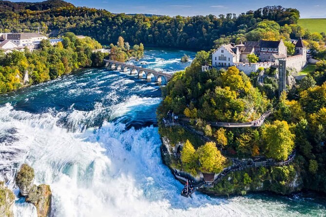 The Rhine Falls from the air, white water below a wooded rock