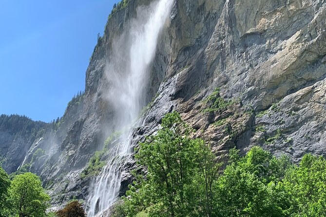 A waterfall dropping down a sheer rock wall in an Alpine valley